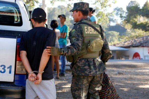 A military police officer detains a man, traveling with other Hondurans in a new caravan of migrants toward the United States, due an arrest warrant, at a checkpoint in San Marcos, Honduras, on Jan. 15, 2020. (Stringer/Reuters)