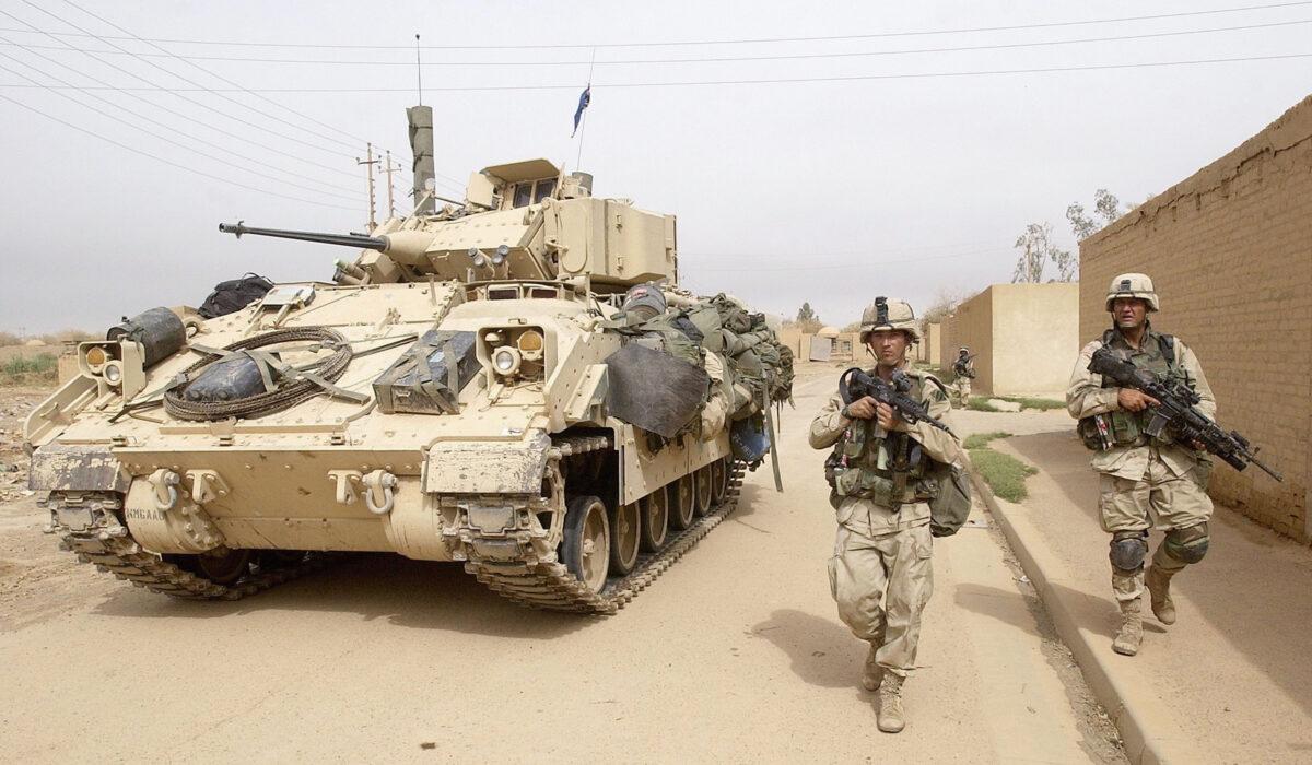 U.S. Army 3rd Division 3-7 infantry soldiers use a Bradley fighting vehicle for cover as they conduct a neighborhood patrol on the outside perimeter of the Baghdad International Airport on April 8, 2003. (Scott Nelson/Getty Images)