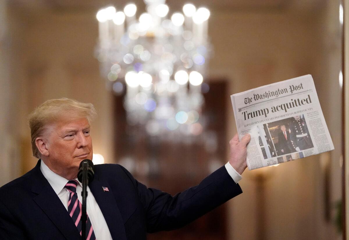 President Donald Trump holds a copy of The Washington Post as he speaks in the East Room of the White House one day after the U.S. Senate acquitted on two articles of impeachment, on Feb. 6, 2020. (Drew Angerer/Getty Images)