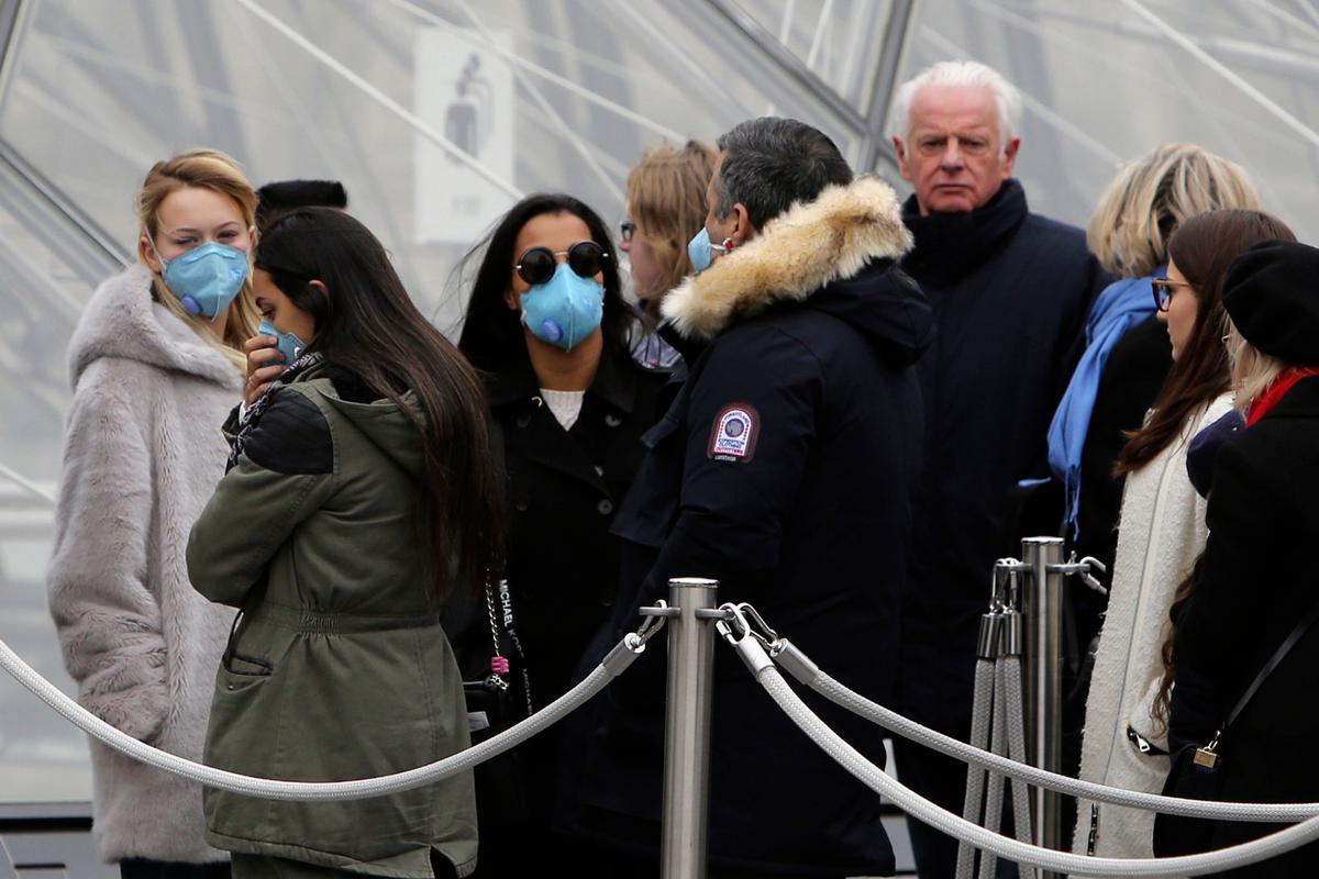 Tourists, some wearing a mask, queue to enter the Louvre museum in Paris, France, on Feb. 28, 2020. (Rafael Yaghobzadeh/AP Photo)