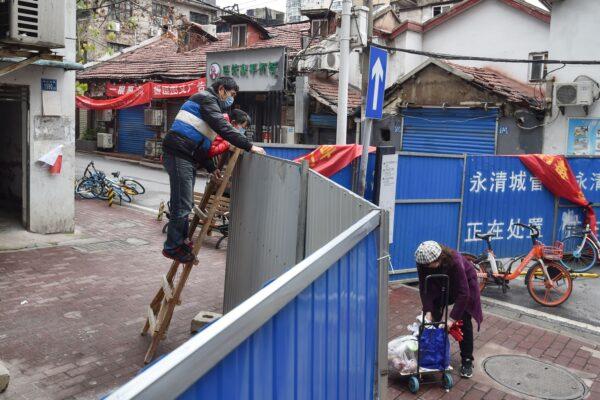 Residents delivering foods over a wall closing off a street in Wuhan in China's central Hubei province on March 3, 2020. (STR/AFP via Getty Images)