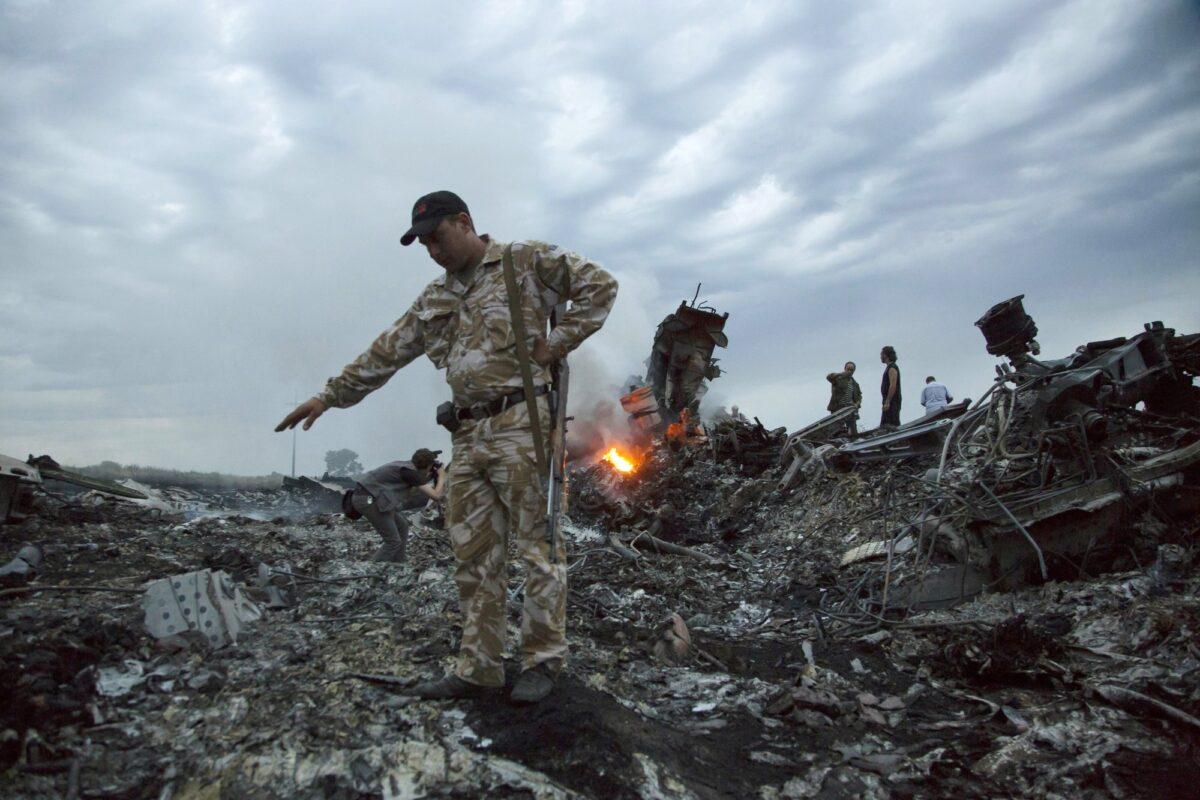 People walk amongst the debris at the crash site of the MH17 passenger plane near the village of Grabovo, Ukraine, on July 17, 2014. (Dmitry Lovetsky/File via AP)