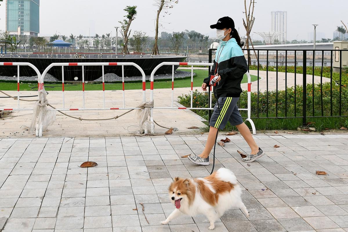 A woman wearing a face mask as a preventive measure against the spread of COVID-19 walks her dog in Hanoi, Vietnam, on March 20, 2020. (Nhac Nguyen/AFP via Getty Images)