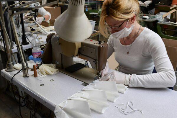 An employee wearing a protective mask sews surgical masks at a leather workshop turned into a mask factory, close to Vigevano, Lombardy, on March 19, 2020. (Miguel Medina/AFP via Getty Images)