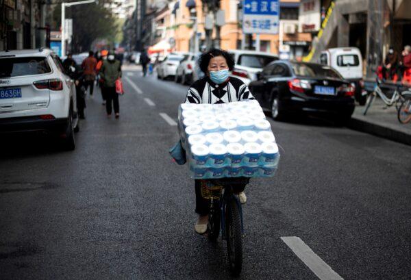 A woman is cycling along a street in Wuhan, China on April 1, 2020. (Noel Celis/AFP via Getty Images)