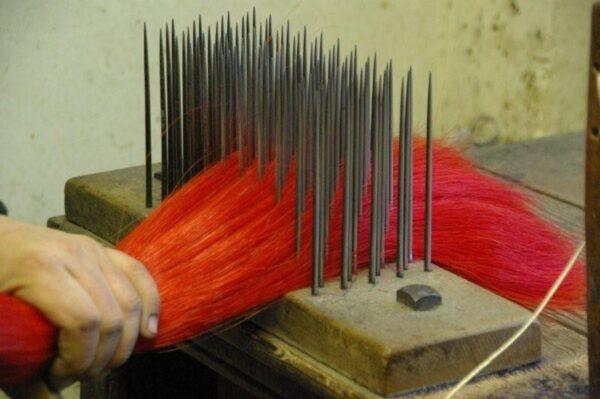 Dyed horsehair is combed on a hackle in preparation for weaving. (John Boyd Textiles Ltd.)