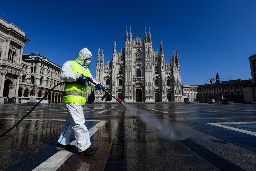 An employee wearing protective gear, working for environmental services company AMSA, sprays disinfectant on Piazza Duomo in Milan, on March 31, 2020, during the country's lockdown aimed at curbing the spread of the COVID-19 infection, caused by the novel coronavirus. (PIERO CRUCIATTI/AFP via Getty Images)