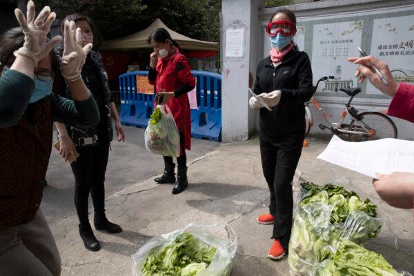 A resident in red collects her vegetable from other resident volunteers in Wuhan in central China's Hubei Province, China, on April 6, 2020. (Ng Han Guan/AP Photo)