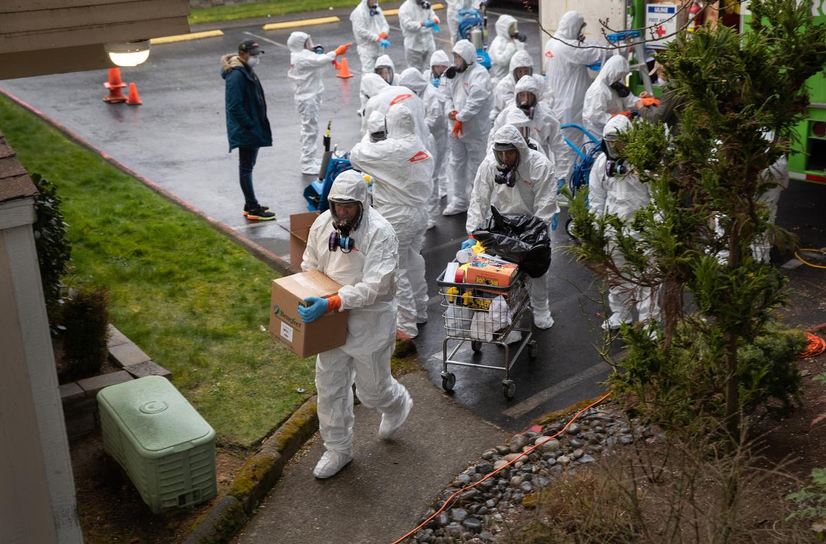 A cleaning crew wearing protective clothing (PPE) takes disinfecting equipment into the Life Care Center on March 12, 2020, in Kirkland, Washington. (John Moore/Getty Images)