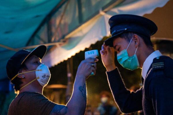 A police officer getting his body temperature measured by a bouncer as he enters a bar in Hong Kong, China, on March 29, 2020. (Anthony Kwan/Getty Images)