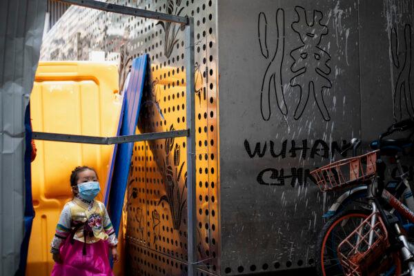 A girl wearing a face mask crosses a barricade in Wuhan, China's central Hubei Province on April 7, 2020. (Noel Celis /AFP) via Getty Images)