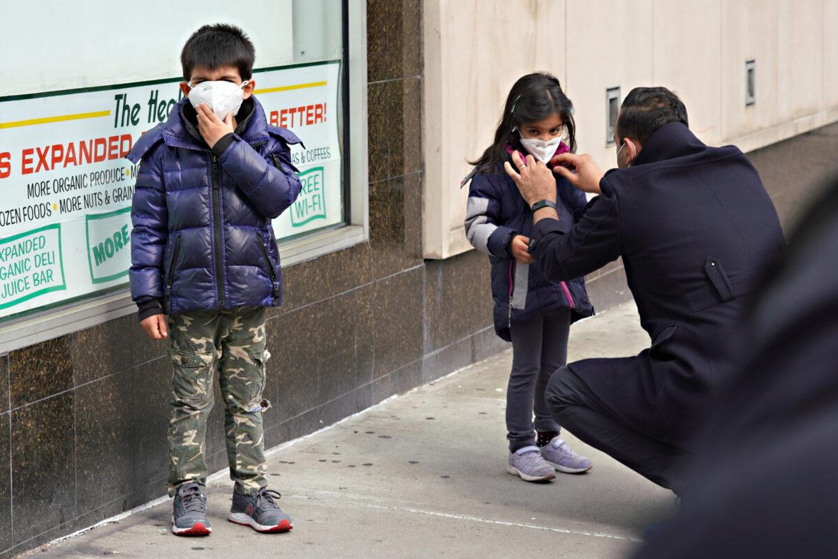 A man adjusts a child's mask in New York City, N.Y., on April 5, 2020. (Cindy Ordt/Getty Images)