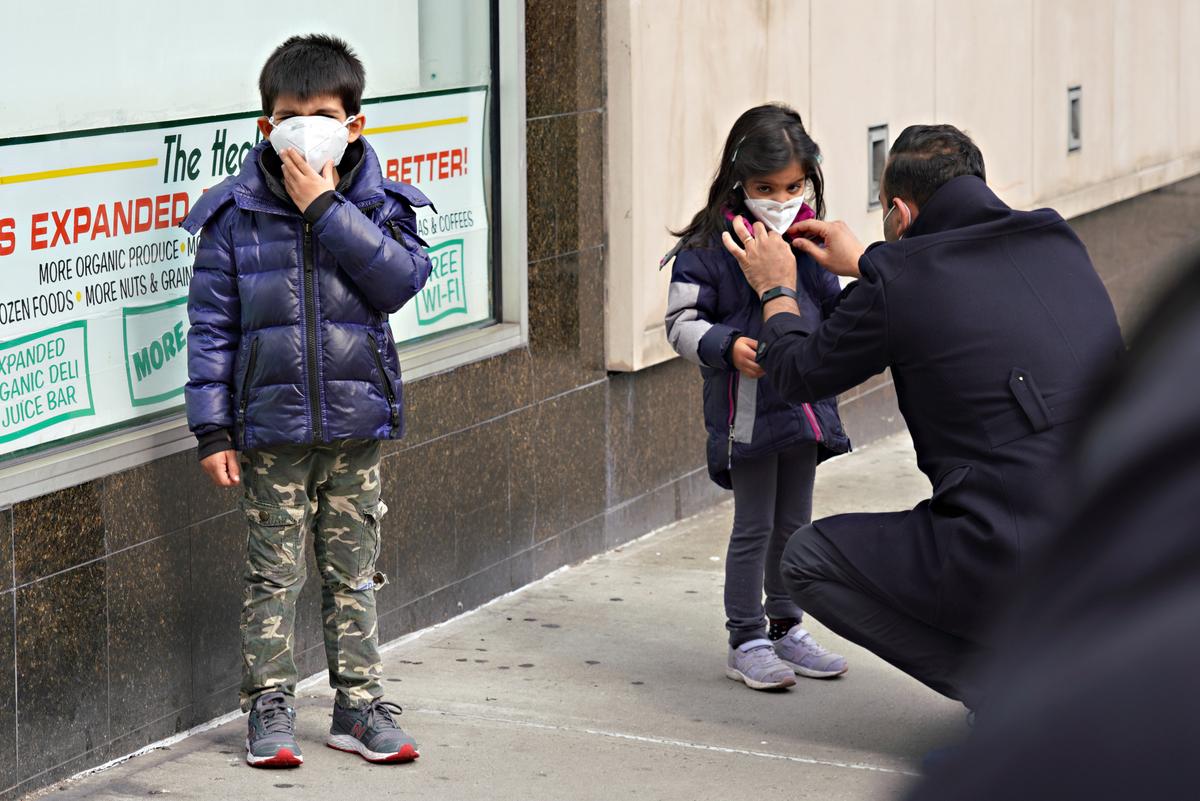 A man adjusts a child's protective mask in New York City on April 5, 2020. (Cindy Ordt/Getty Images)