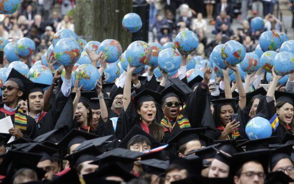 Graduates of Harvard's John F. Kennedy School of Government hold aloft inflatable globes as they celebrate graduating during Harvard University's commencement exercises in Cambridge, Mass., on May 30, 2019. (Steven Senne/AP Photo)