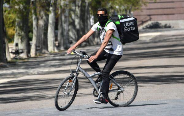 An Uber Eats delivery man with his face covered rides his bike in Montpellier, southern France on April 3, 2020. (Pascal Guyot/AFP via Getty Images)