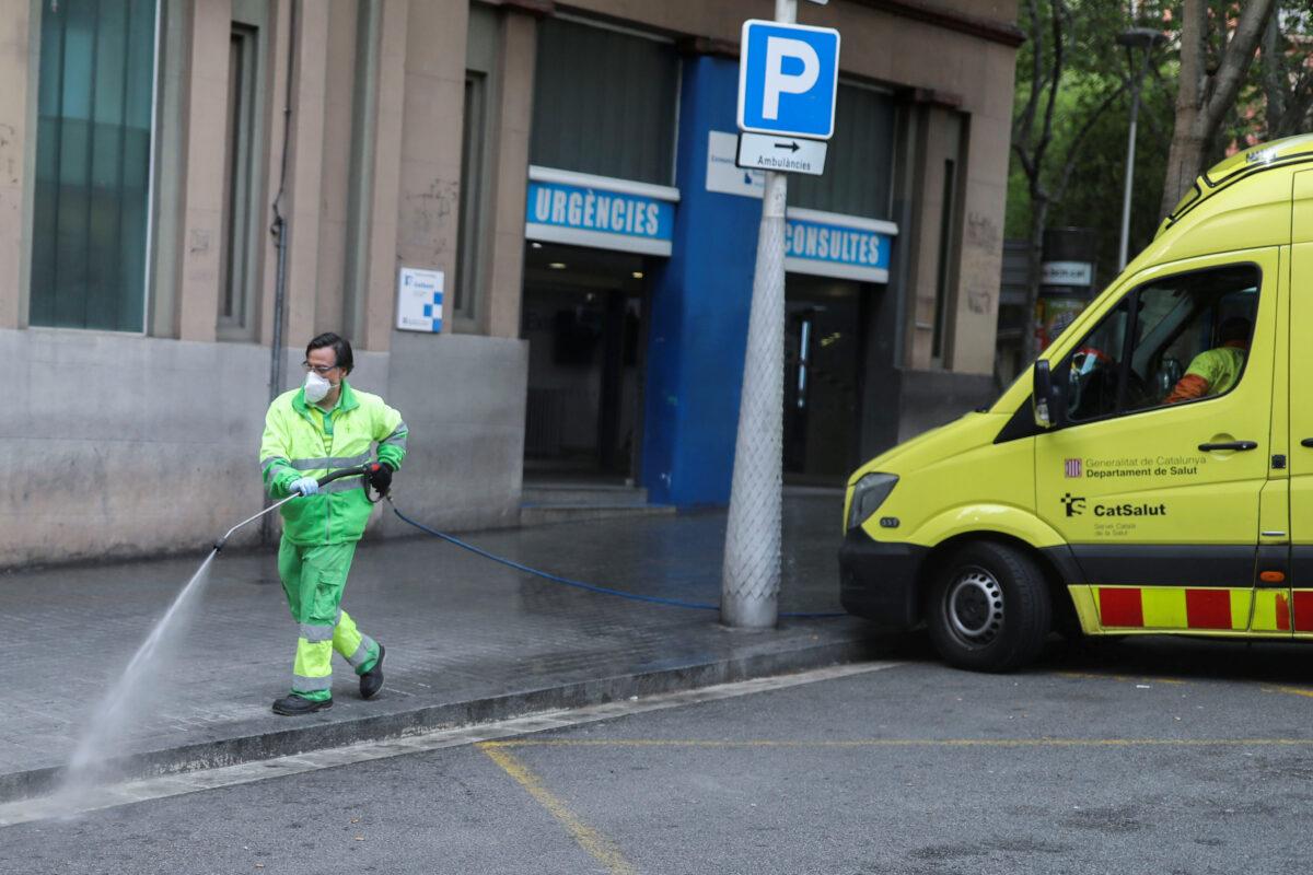 A worker washes the street outside of a medical emergency facility during the CCP virus outbreak, in Barcelona, Spain on April 7, 2020. (Nacho Doce/Reuters)
