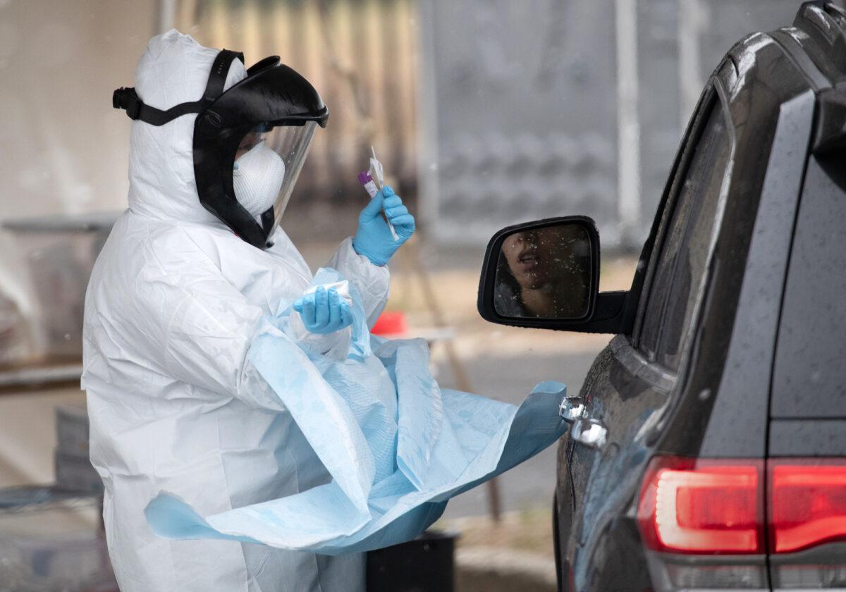 A nurse dressed in personal protective equipment prepares to give a COVID-19 swab test at a drive-through testing station in Stamford, Connecticut, on March 23, 2020. (John Moore/Getty Images)