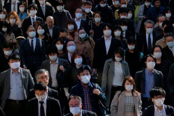 Mask-clad commuters head to work through a street connecting from Shinjuku railway station in Tokyo on April 9, 2020. (Kazuhiro Nogii/AFP via Getty Images)