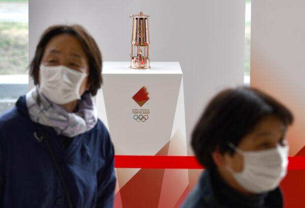 Women wearing masks amid concerns of the CCP virus leave after looking at the Olympic Flame which was passed from Tokyo 2020 to Fukushima Prefecture at the J-Village National Training Center in Naraha on April 2, 2020. (Kazuhiro Nogi/AFP via Getty Images)