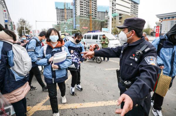 A police officer gestures at the entrance of a school as middle school and high school students return after delays because of the CCP virus outbreak in Huaian, Jiangsu Province, China, on March 30, 2020. (STR/AFP via Getty Images)