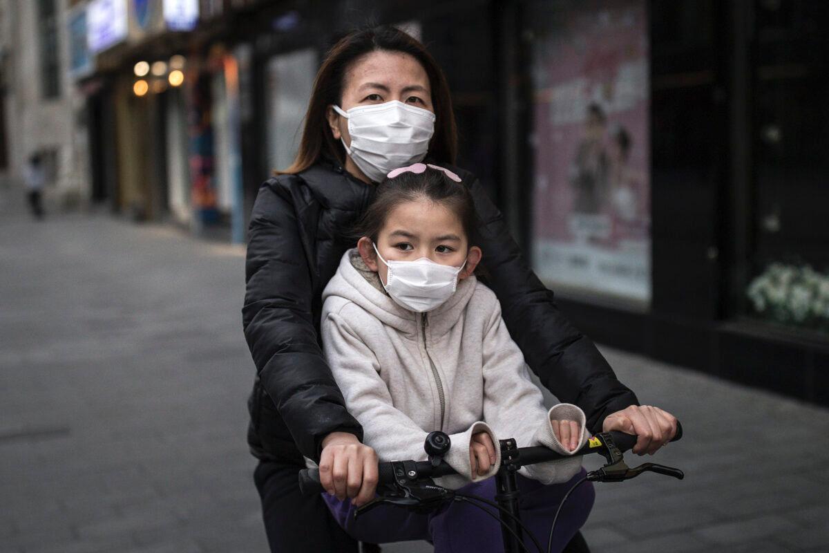 The mother wear a mask while ride bike with her daughter in Wuhan, Hubei Province, China, on April 11, 2020. (Getty Images)