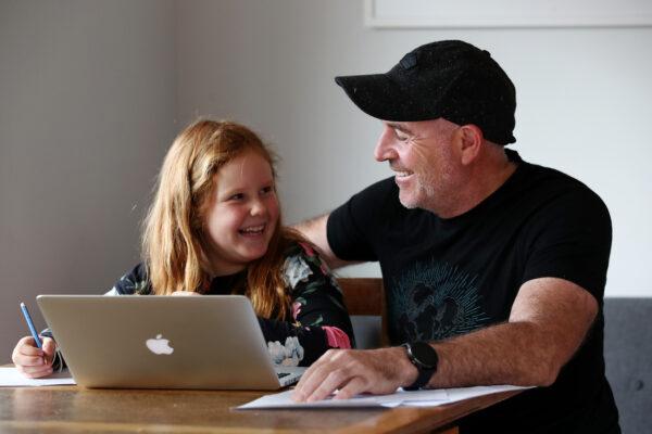Nina Goodall (8) works on her lessons online for the first day of term with help from her dad Seamus Goodall before he leaves for work while in lockdown at their home in Kaipara Flats in Auckland, New Zealand on April 15, 2020. (Fiona Goodall/Getty Images)