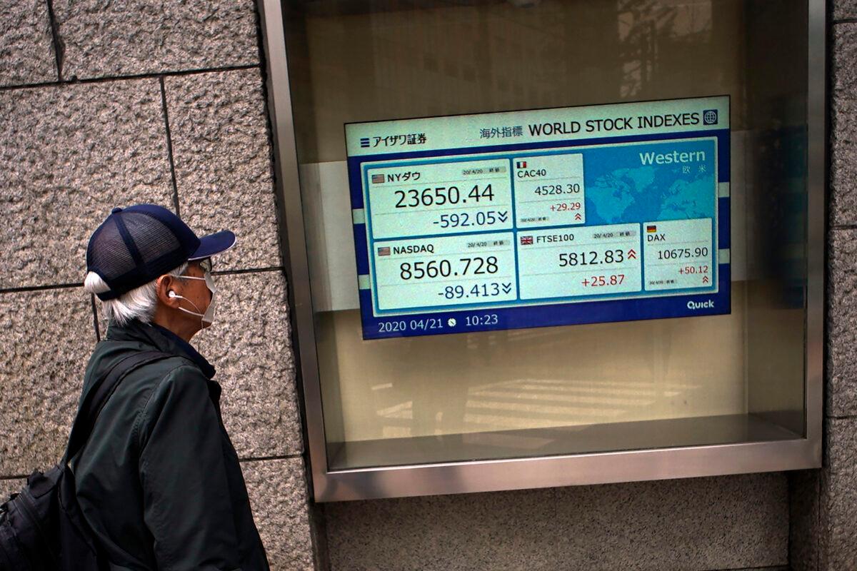 A man wearing a mask against the spread of the CCP virus looks at an electronic stock board showing world stock indexes at a securities firm in Tokyo, Japan on April 21, 2020. (Eugene Hoshiko/AP Photo)