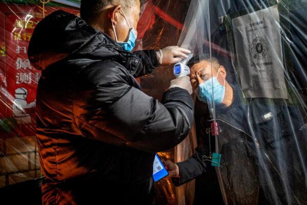 A staff member (L) checking the body temperature of a resident before he enters a residential compound in Mudanjiang in China's northeastern Heilongjiang province on April 20, 2020. (STR/AFP via Getty Images)