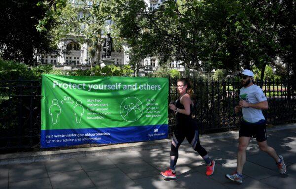 Runners pass a social distancing sign in London on April 26, 2020. (Alex Davidson/Getty Images)