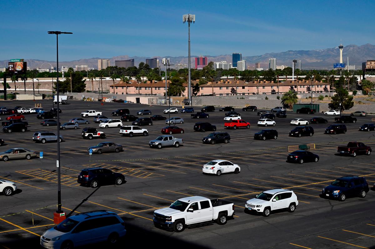 The Las Vegas Strip skyline is seen as vehicles line up the parking lot around Boulder Station Hotel & Casino as they wait to get into a drive-thru Three Square Food Bank emergency food distribution site in response to an increase in demand amid the COVID-19 pandemic in Las Vegas, Nevada, on April 29, 2020. (David Becker/AFP via Getty Images)