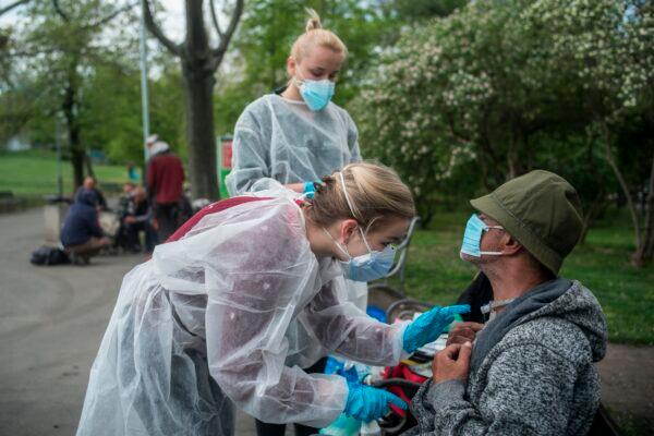 Amid restrictions due to the novel CCP virus COVID-19 pandemic, medics of the Faculty of Medicine of Charles University treat a homeless man in front of the Prague main railway station in Prague, Czech Republic, on April 28, 2020. (Michal Cizek/AFP/Getty Images)