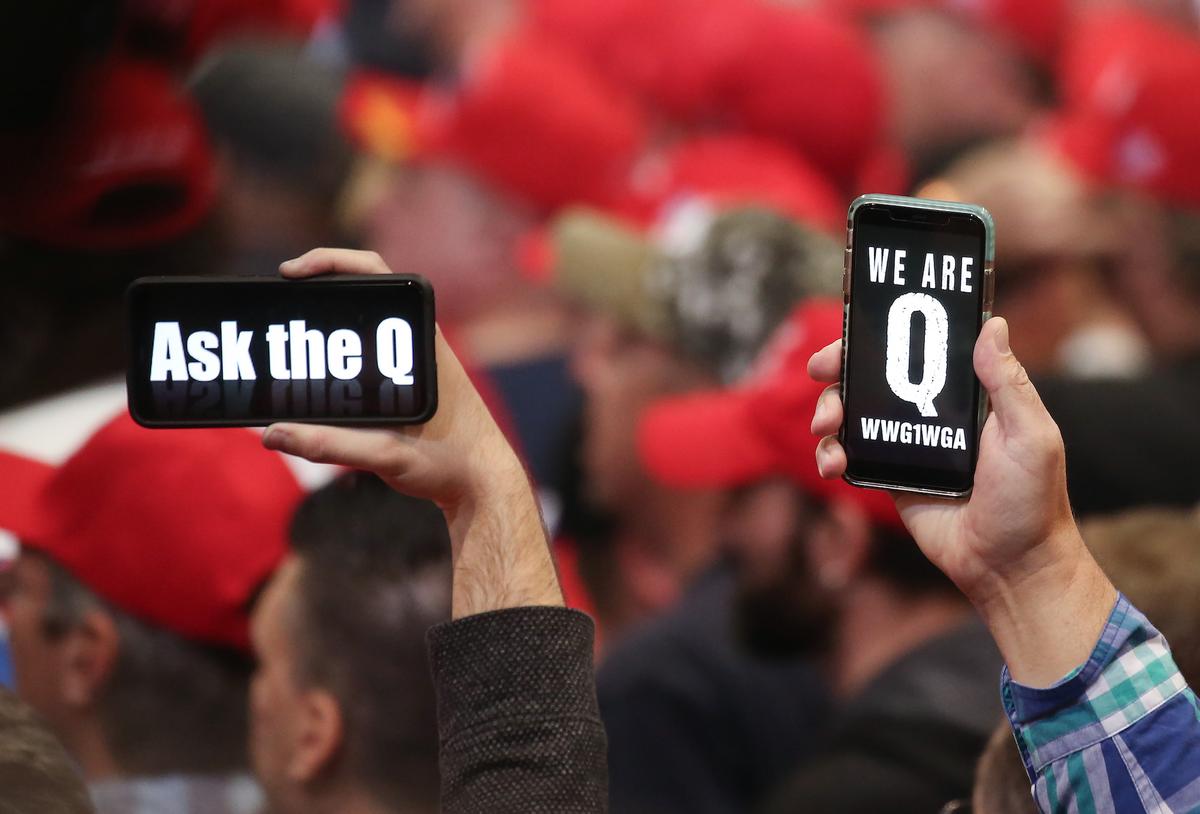 People hold up smartphones with QAnon-related messages on display, at a rally in Las Vegas, Nev., on Feb. 21, 2020. (Mario Tama/Getty Images)