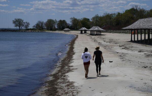 Women walk along the beach on the Long Island Sound on Tod's Point in Old Greenwich, Conn. on May 7, 2020. The beach and park opened partially again for residents to walk, run and cycle on the beach but no laying in the sand or going in the water. (Timothy A. Clary/AFP via Getty Images)