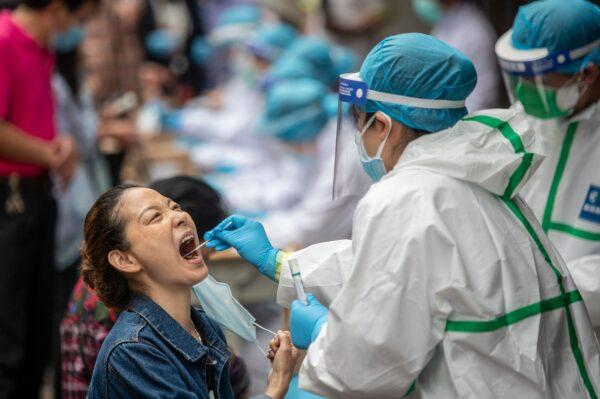 A medical worker takes a swab sample from a resident to be tested for the CCP virus in Wuhan, China, on May 15, 2020. (STR/AFP via Getty Images)