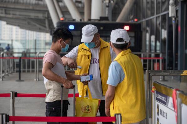 A staff member screens the body temperature of a passenger at the entrance of the Wuhan Railway Station in Wuhan, China, on May 28, 2020. (STR/AFP via Getty Images)