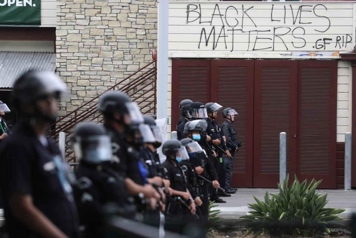 LAPD officers keep watch beneath graffiti reading 'Black Lives Matters' during demonstrations following the death of George Floyd, in Los Angeles, Calif., on May 30, 2020. (Mario Tama/Getty Images)