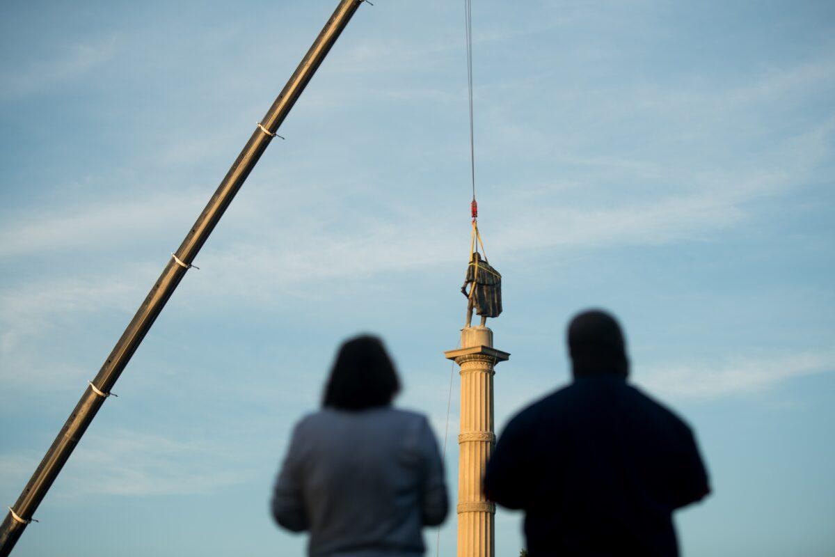 People look at the statue of John C. Calhoun atop the monument in his honor as workers prepare to relocate the memorial from Marion Square in Charleston, S.C., on June 24, 2020. Local officials planned to move the statue to a museum or educational institution. (Sean Rayford/Getty Images)