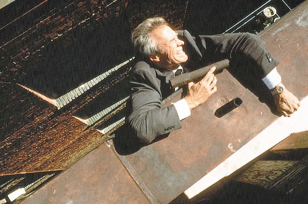 Frank (Clint Eastwood) hangs on to a building ledge and life, in "In the Line of Fire." (Columbia Pictures)