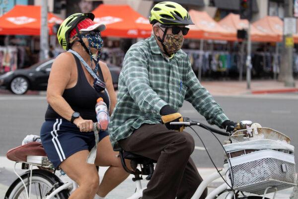 A couple ride a tandem bike at Huntington Beach, Calif., on July 1, 2020. (Reuters/Mike Blake)