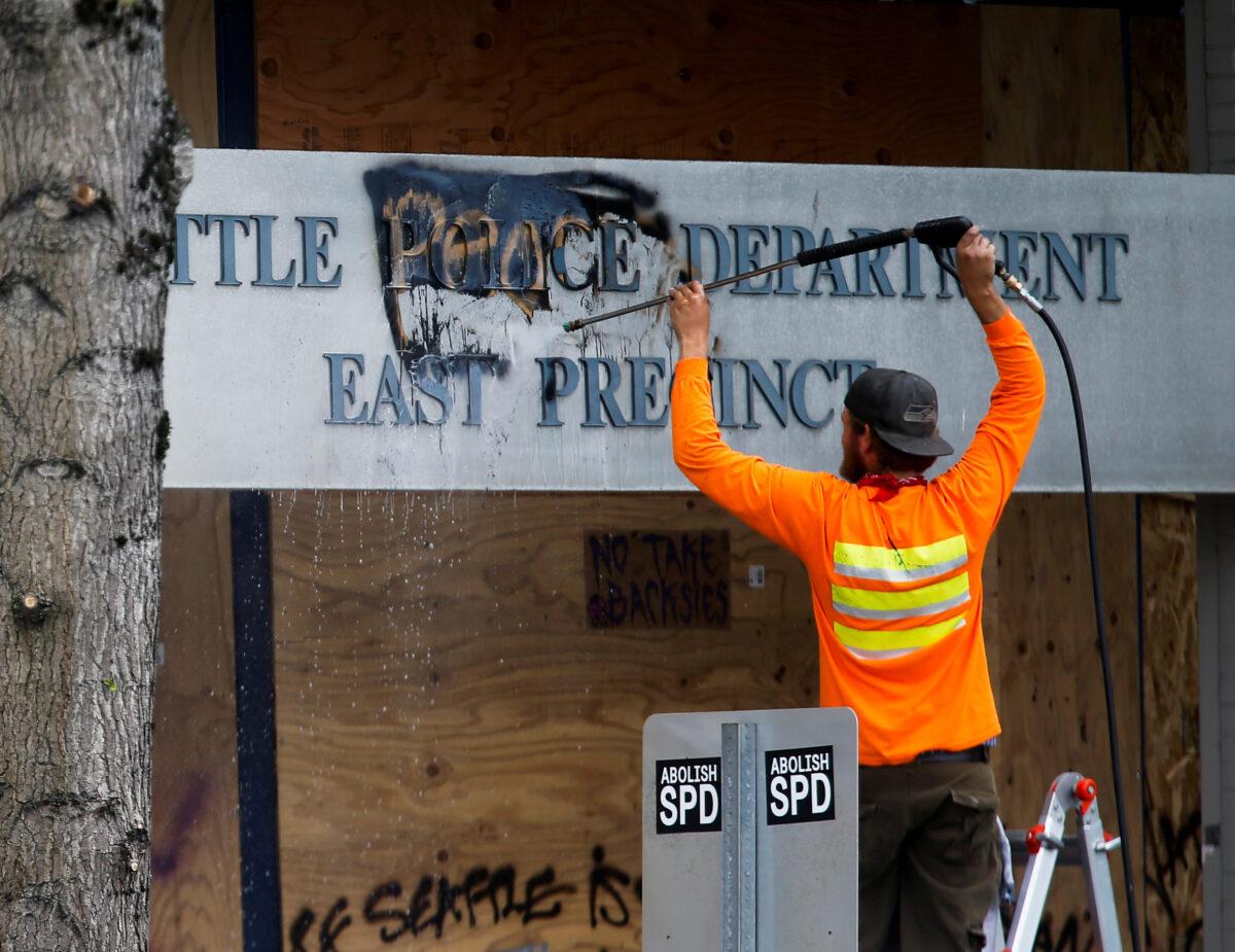 A worker cleans off the word "people" graffitied over the word "police" at the Seattle Police Department's East Precinct as they retake the Capitol Hill Occupied Protest (CHOP) area in Seattle on July 1, 2020. (Lindsey Wasson/Reuters)