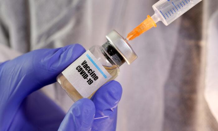 A woman holds a small bottle labeled with a "Vaccine COVID-19" sticker and a medical syringe in this illustration taken on April 10, 2020. (Dado Ruvic/Illustration/File Photo/Reuters)