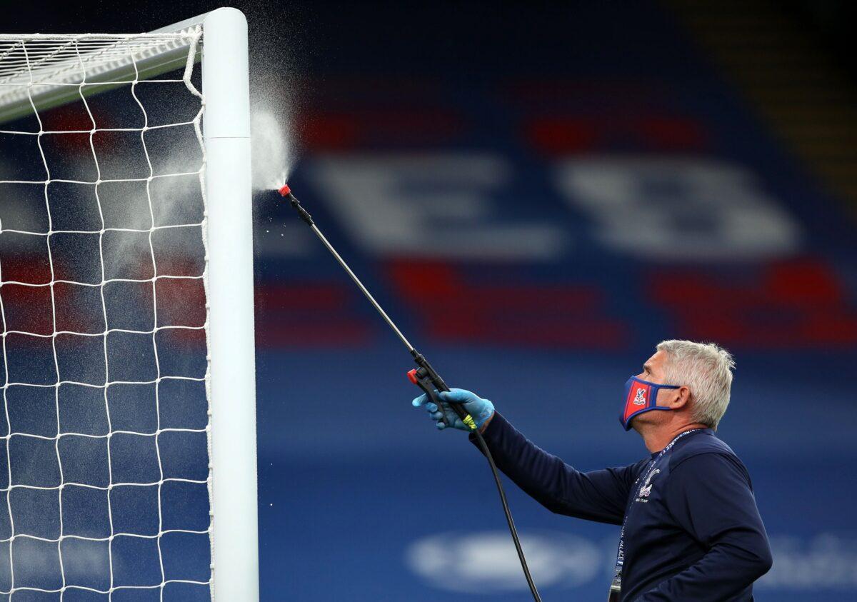 A member of staff disinfects goal posts during a drinks break in a Premier League match in London, UK, on July 7, 2020. (Peter Cziborra/Pool/Getty Images)