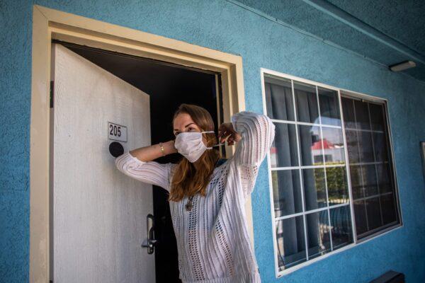A woman puts a mask on at a motel that provided rooms to homeless people through the NGO St. Joseph Center, in Venice Beach, Calif., on April 26, 2020. (Apu Gomes/AFP via Getty Images)