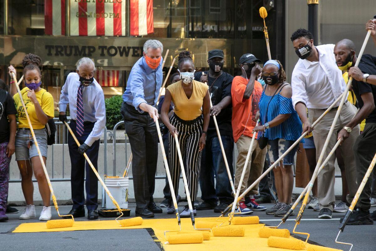 Mayor Bill de Blasio, third from left, participates in painting Black Lives Matter on Fifth Avenue in front of Trump Tower in New York City on July 9, 2020. The mayor's wife, Chirlane McCray, is fourth from left and Rev. Al Sharpton is second from left. (Mark Lennihan/AP Photo)