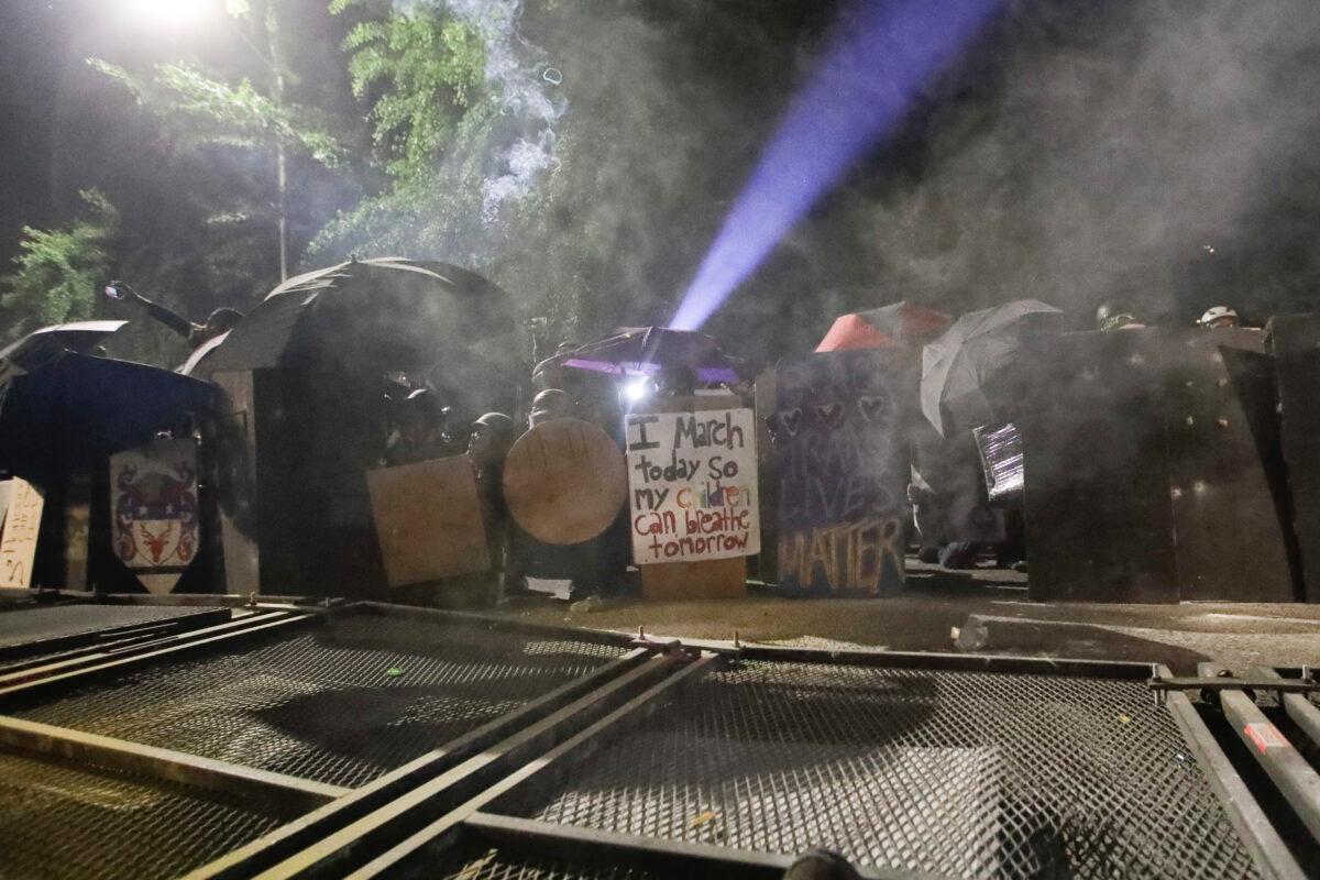 Rioters shield themselves after toppling a fence as federal officers deploy tear gas at the Mark O. Hatfield United States Courthouse in Portland, Ore., on July 26, 2020. (Marcio Jose Sanchez/AP Photo)