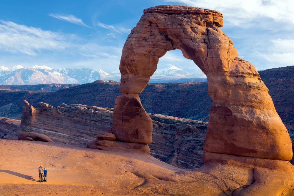 A family stands next to Delicate Arch in Arches National Park. (IrinaK/Shutterstock)