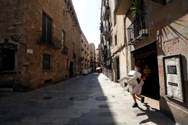 A staff member of a bar carries chairs, amid the coronavirus disease (COVID-19) outbreak, in the Gothic quarter in Barcelona, on July 27, 2020. (Albert Gea/Reuters)
