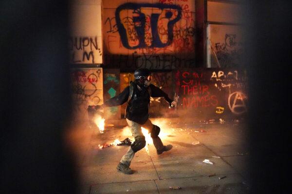 A rioter throws a flaming object toward the Mark O. Hatfield U.S. Courthouse after breaking through the perimeter fence, in Portland, Ore., on July 22, 2020. (Nathan Howard/Getty Images)