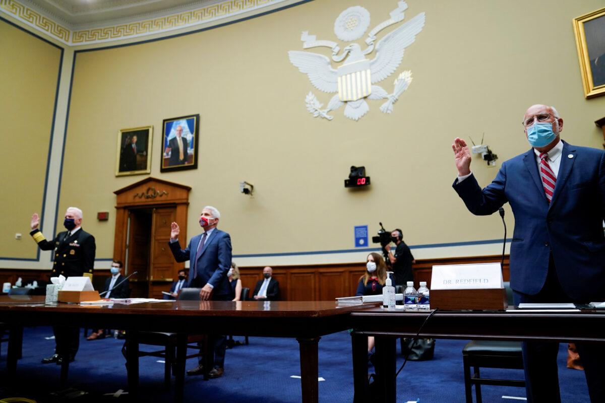 Robert Redfield, director of the Centers for Disease Control and Prevention, from right, Anthony Fauci, director of the National Institute of Allergy and Infectious Diseases, and Admiral Brett Giroir, U.S. assistant secretary for health, swear in to a House Select Subcommittee on the Coronavirus Crisis hearing in Washington, D.C., on July 31, 2020. (Erin Scott/Pool via Reuters)