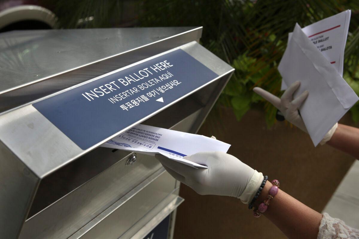 A woman wearing gloves drops off a mail-in ballot at a drop box in Hackensack, N.J., on July 7, 2020. (Seth Wenig/AP Photo)